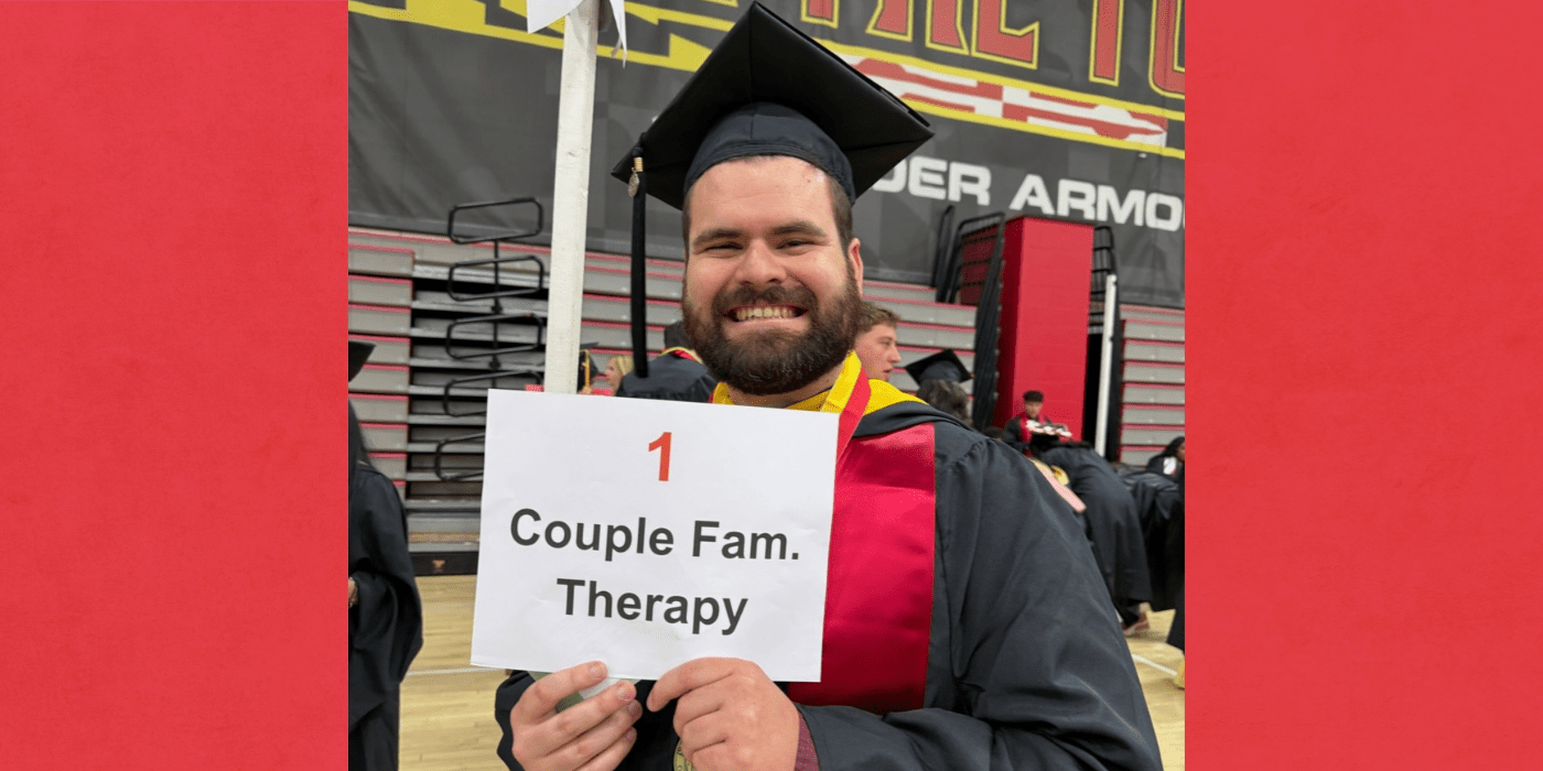 student in graduation dress smiles to camera