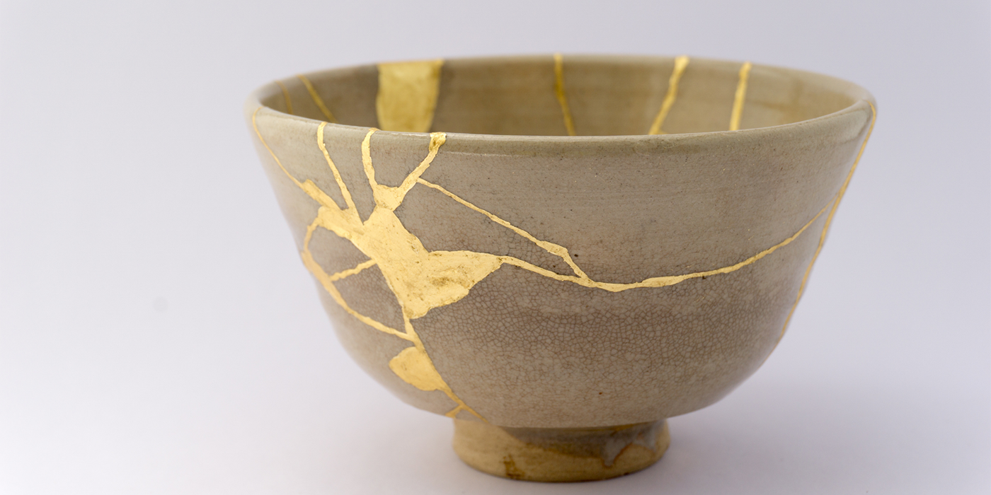 A small Kintsugi pottery bowl with with golden lacquer lines that hold the broken pieces together.