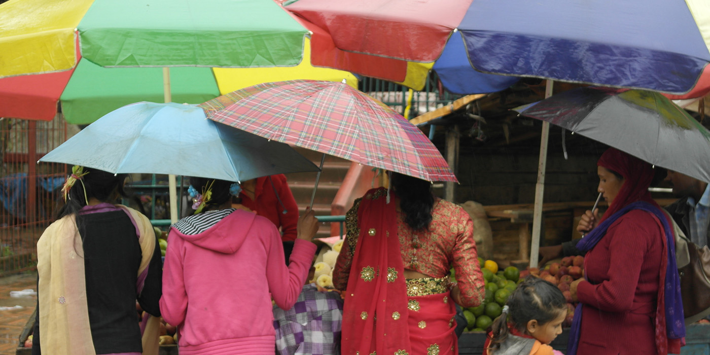 Women and children hold colorful umbrellas at an outdoor food market in Nepal