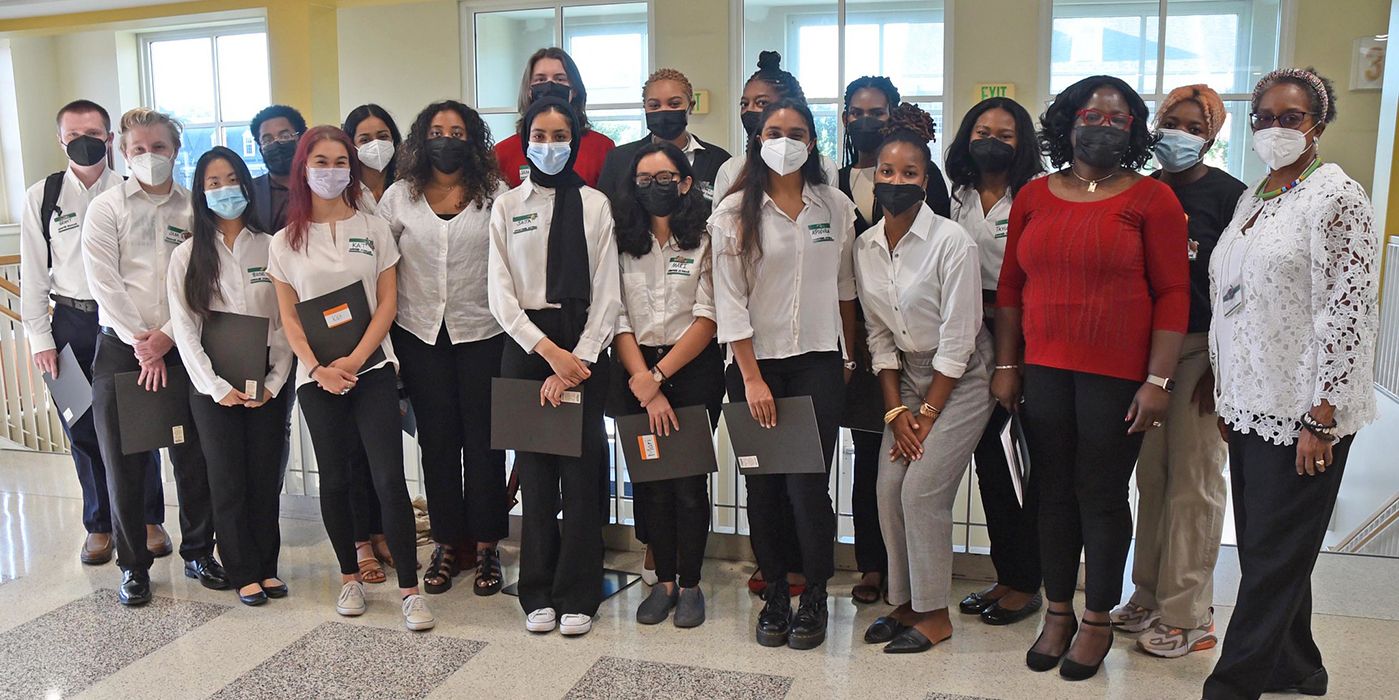 Group of college students wearing face coverings, white tops and black pants poses for a photo at the EJ Symposium at UMD