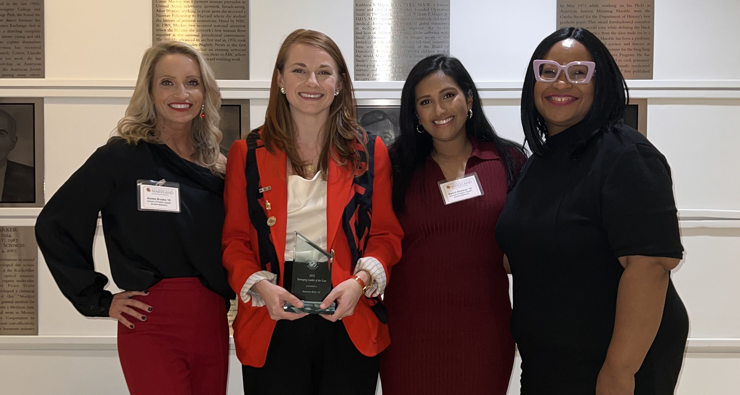 Four women stand next to each smiling, celebrating Jameson Roth, second from left, who is holding a plaque for "Emerging Leader of the Year."