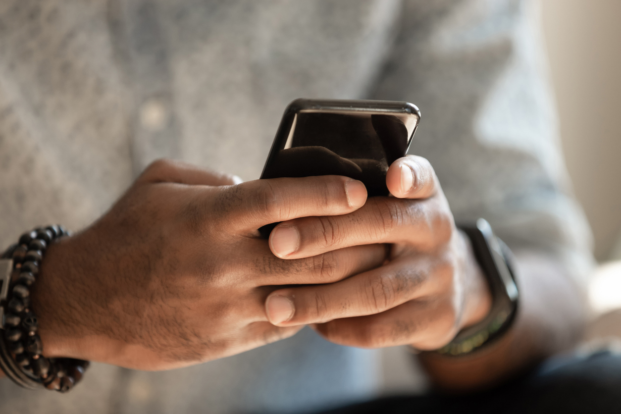 Close up shot showing an African American man's hands holding a cell phone.