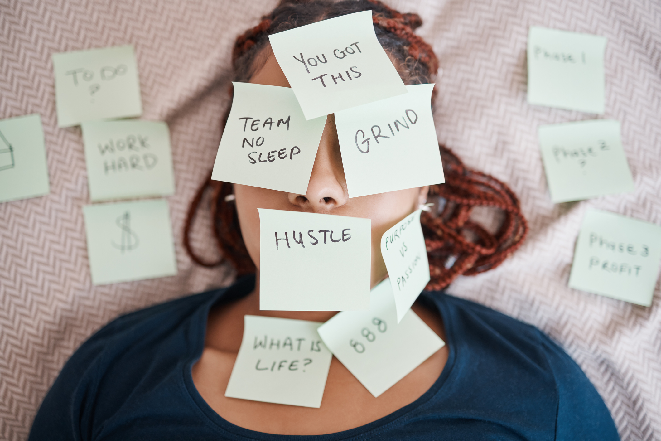 Woman, sticky notes and face in busy schedule, overworked or overwhelmed with work and tasks on bed. 