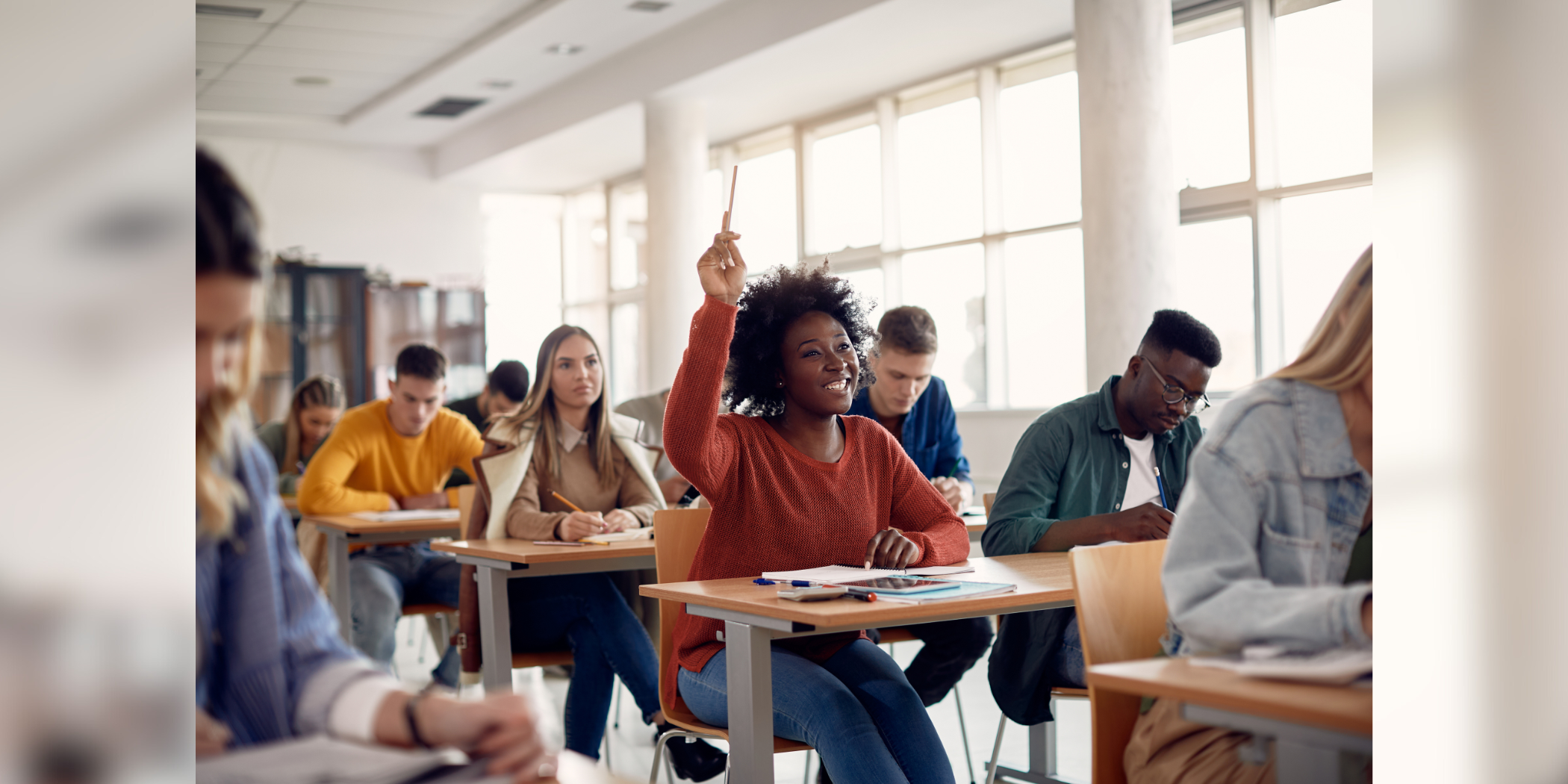 stock image of college classroom with student raising her hand