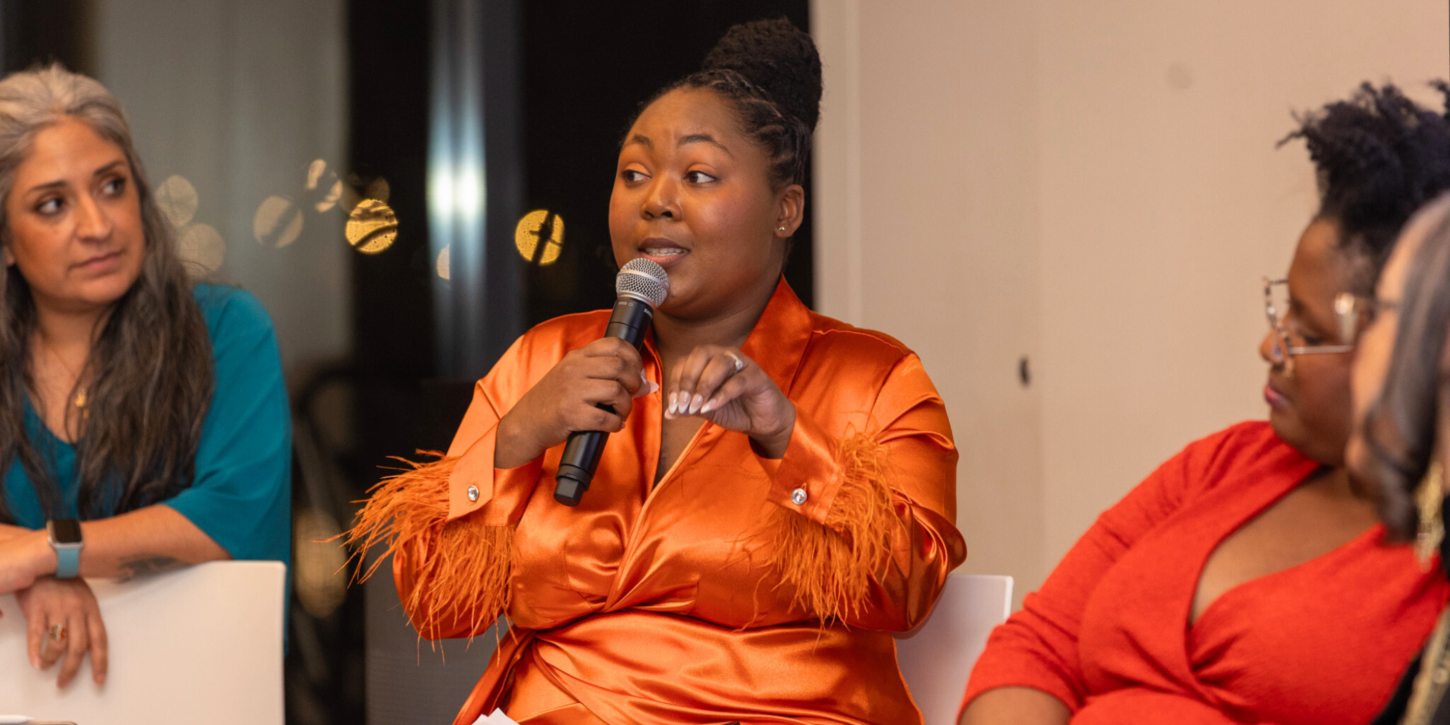 Black female student wearing orange and leading a panel discussion