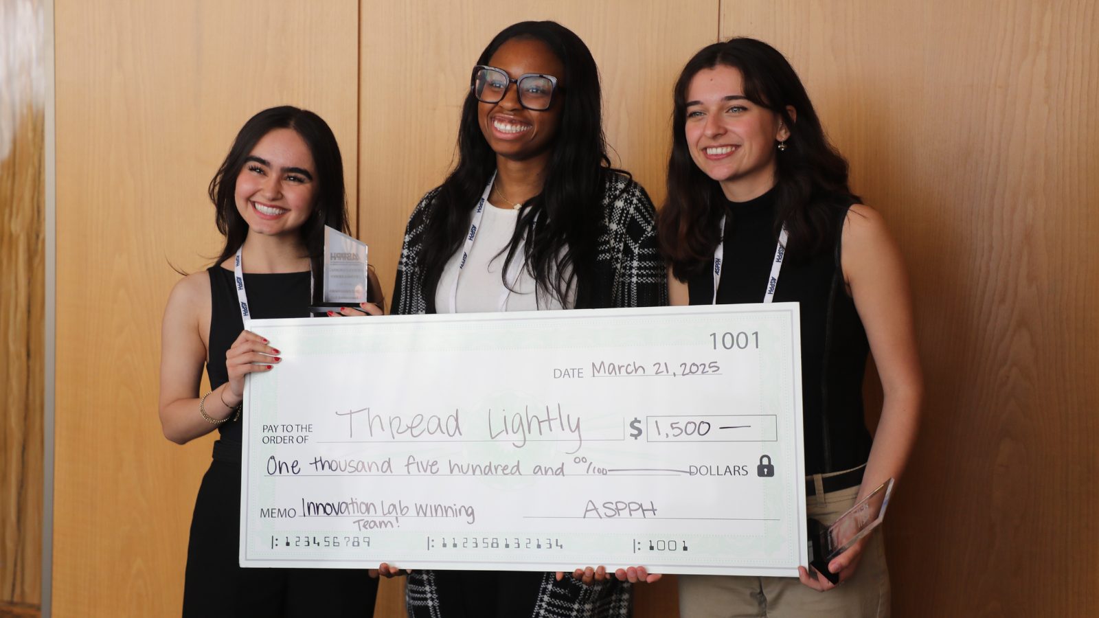three students holding a giant money check