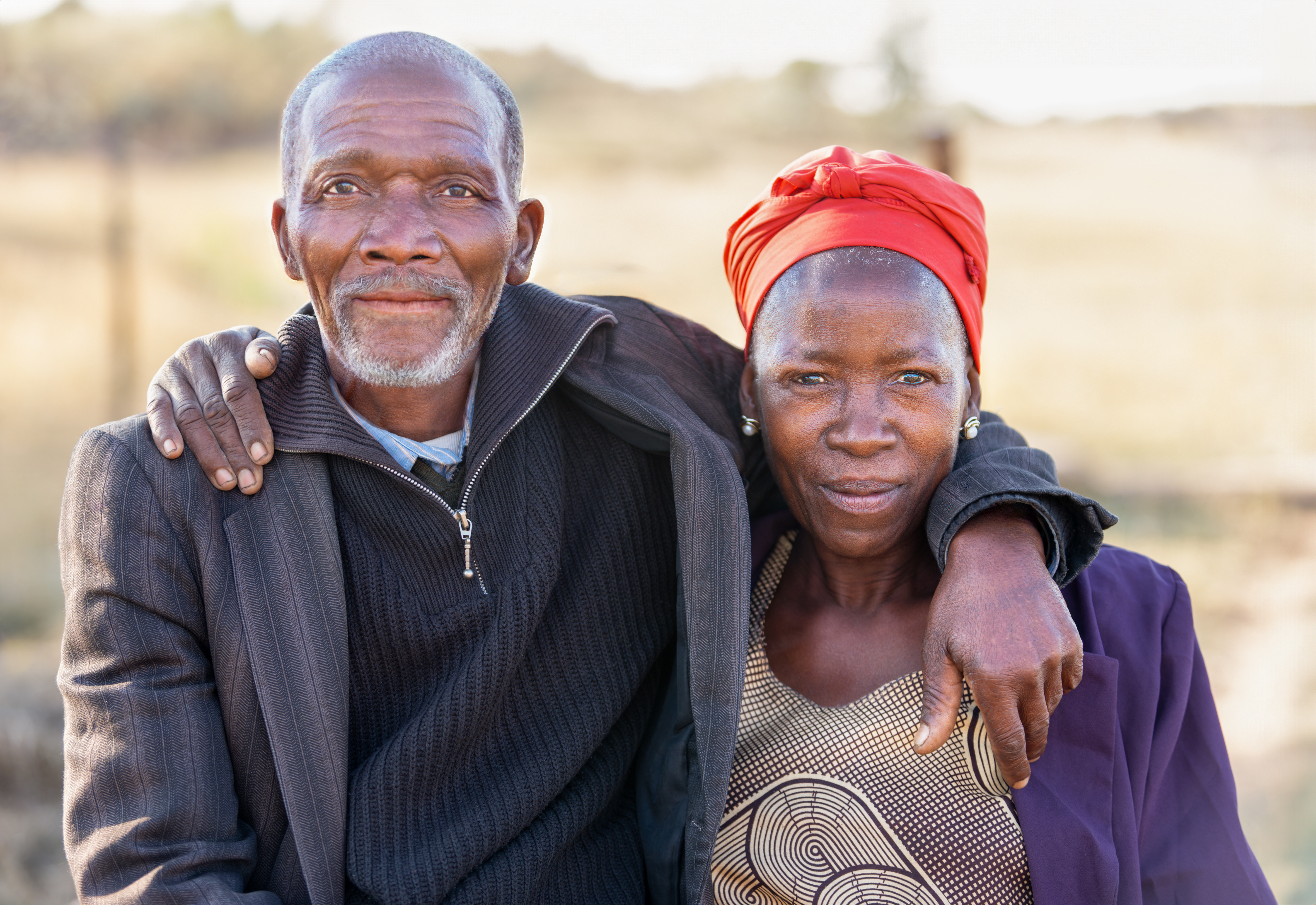 African couple look at the camera, with fields behind