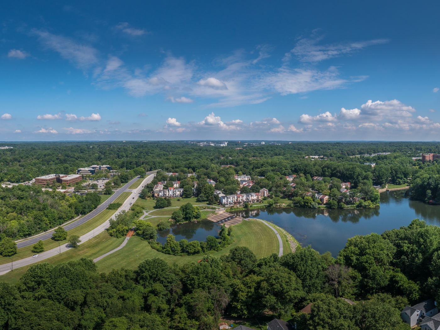 aerial view of rural town with pond and road and tree canopy