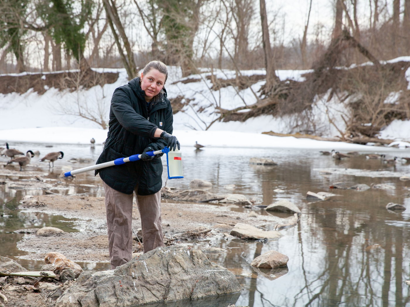 grad student takes a water sample near the Potomac river sewage spill site