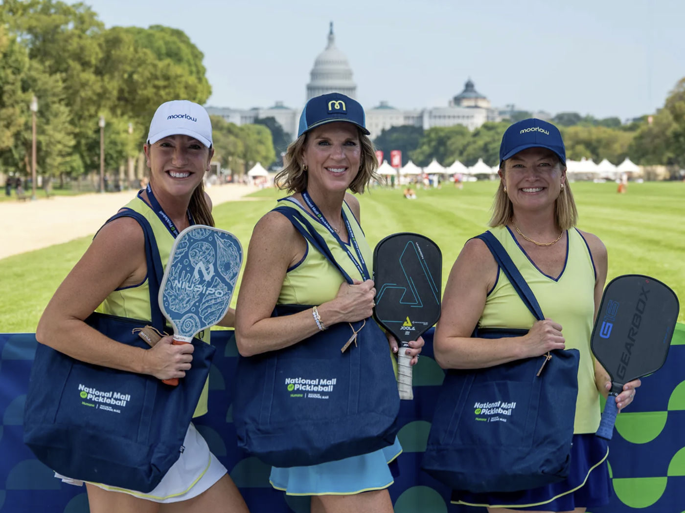 Three women posing with pickleball paddles