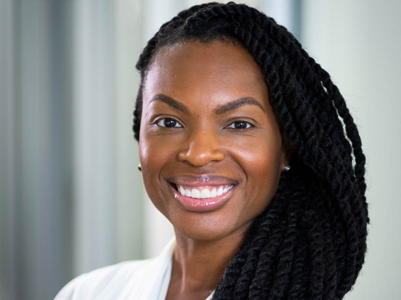 Headshot of a Black woman professor smiling to camera, wearing white shirt