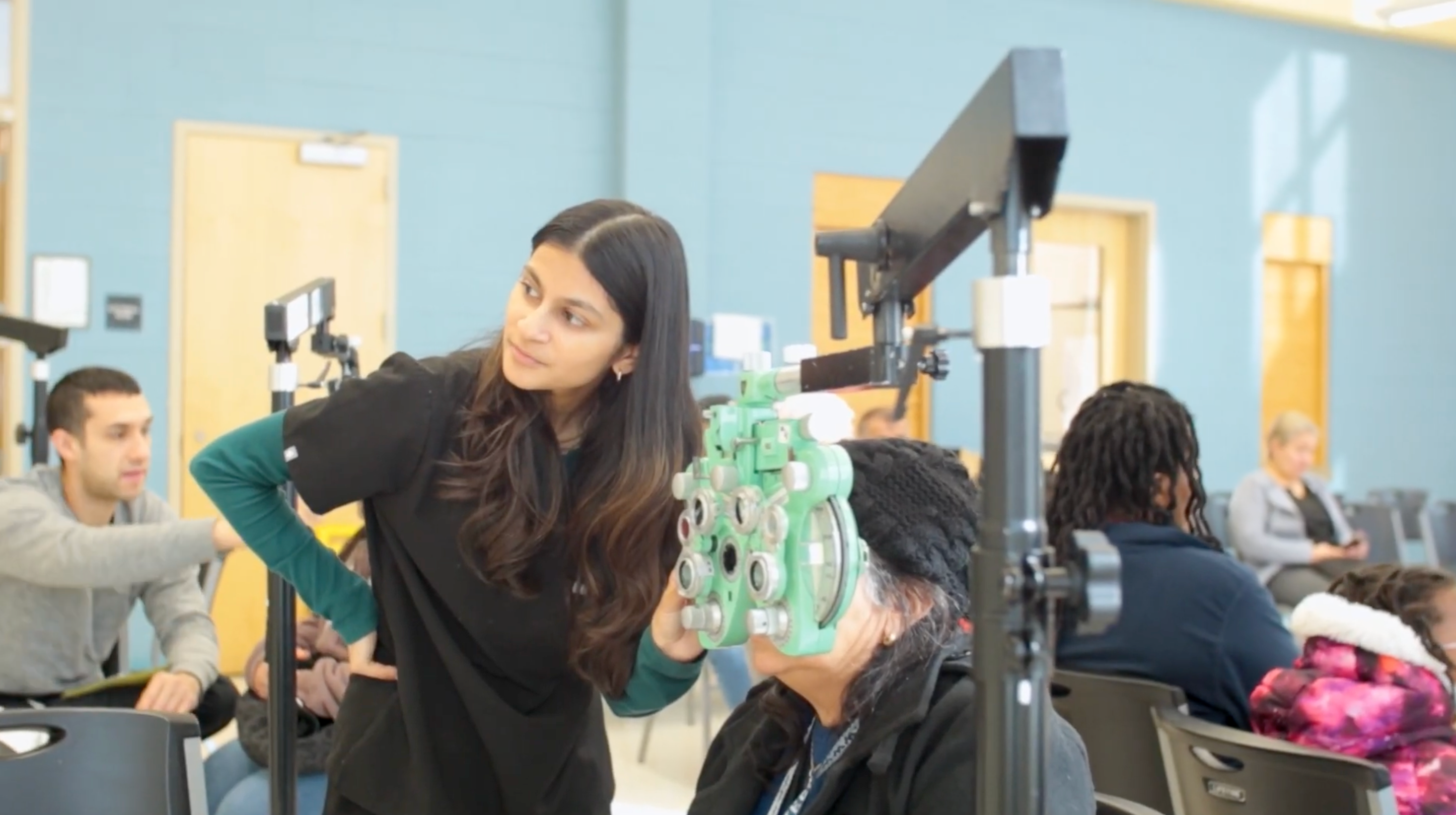 student uses a machine to test the eyes of an elder person