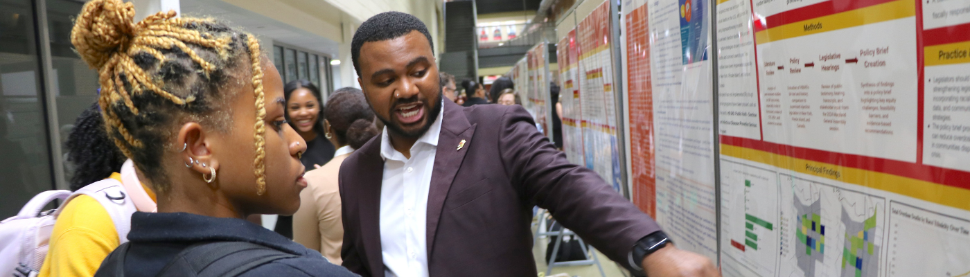 Black male student giving a presentation with a large board