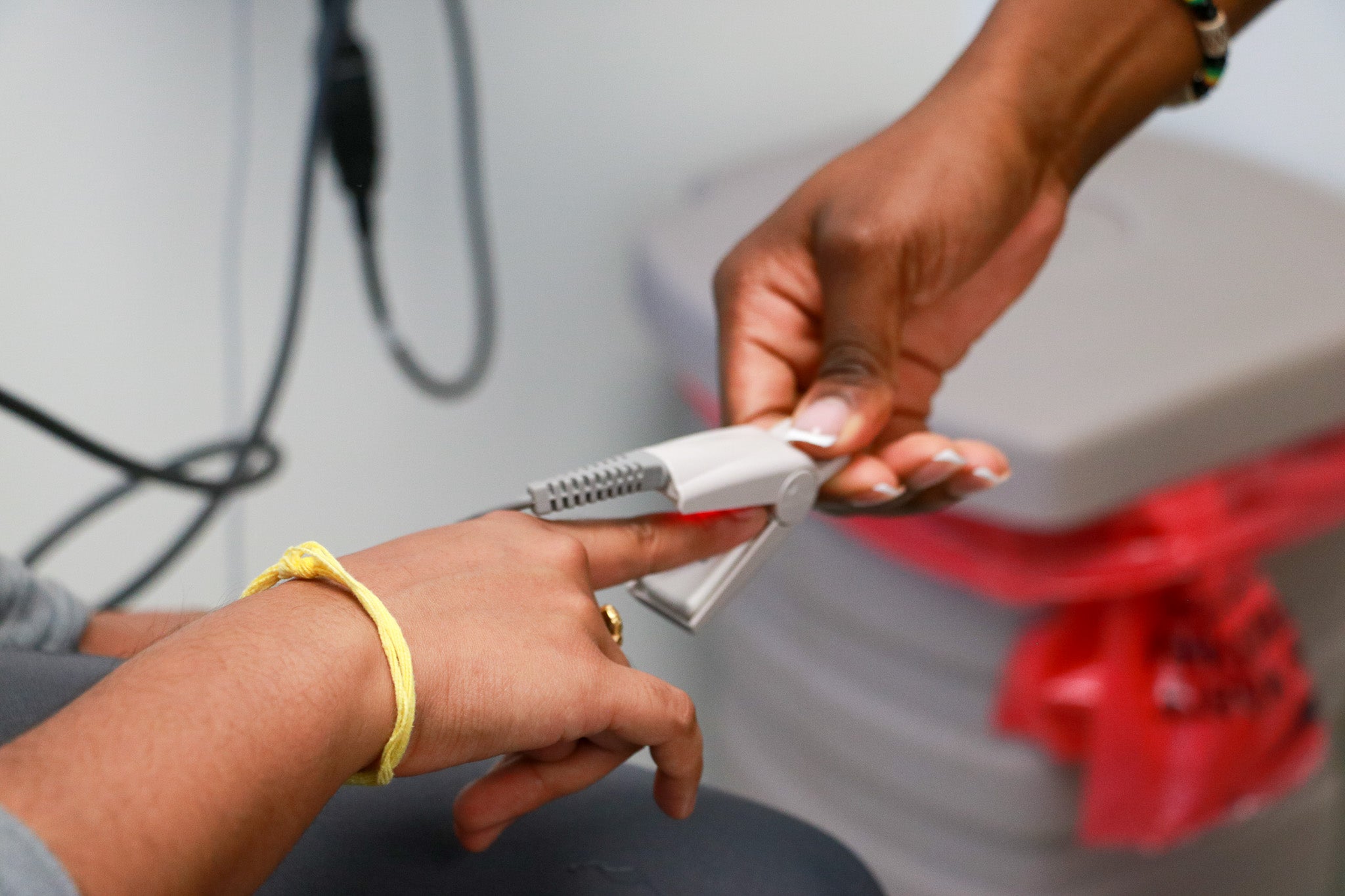 A hand puts a pulse oximeter on another person's fingertip