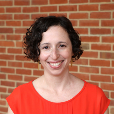 Woman with short brown hair in an orange business top