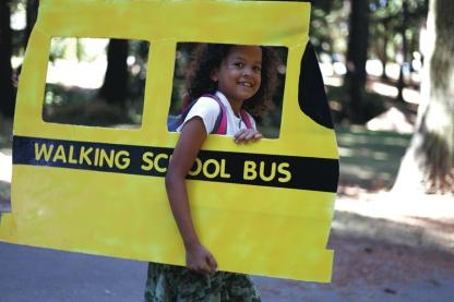 Girl holding a cardboard with school bus illustrated 