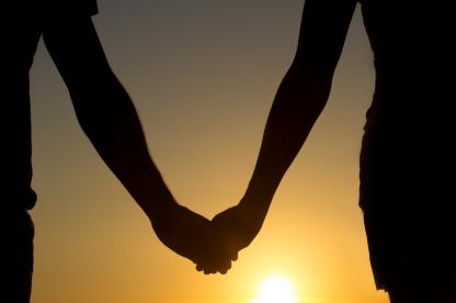 Couple holding hand with sunset in the background