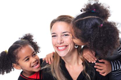 Two small children kissing their mother