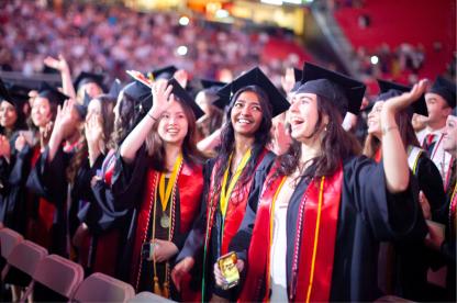 Graduates in caps and gowns celebrate during commencement.
