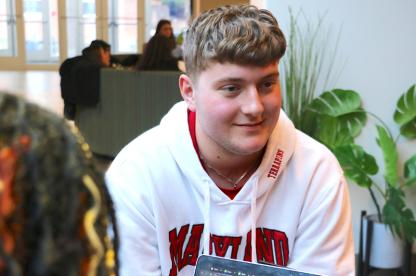 Student in a Maryland hoodie talks with others during a small group meeting.