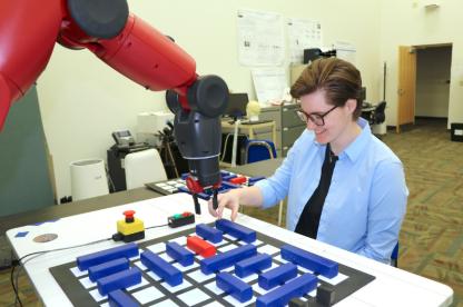 Student playing a game against robotic arm.