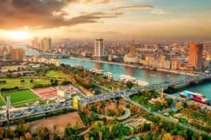 view over cityscape with river and green spaces and high rises with sun setting