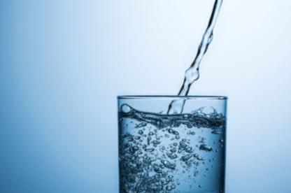 water being poured into a glass, against a blueish background
