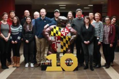 Group of people pose around large Testudo statue and number 10