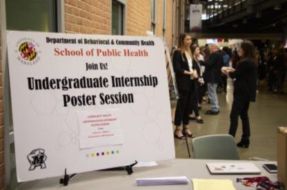 Sign for the School of Public Health Undergraduate Internship Poster Session displayed at a campus event with attendees in the background.