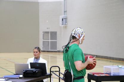 basketball player with brainwave cap on and student researcher observing