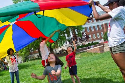 Kids playing under colorful parashute