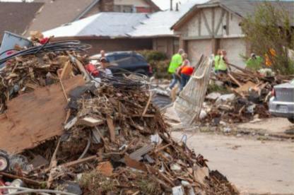 Volunteers clear piles of storm debris and damaged materials from a residential neighborhood.