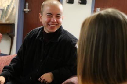 Student sitting down and smiling while having a peer therapy session