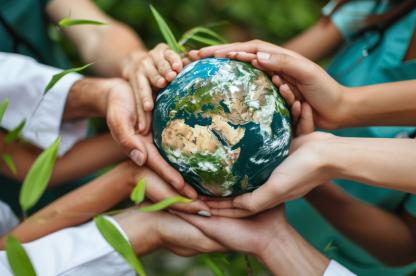 Hands of healthcare professionals and community members holding a globe together, symbolizing global health, collaboration, and environmental sustainability.