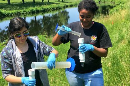 Two female students conducting research near a river