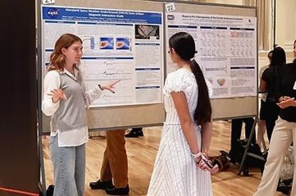 Undergraduate researcher discusses a poster with another attendee.