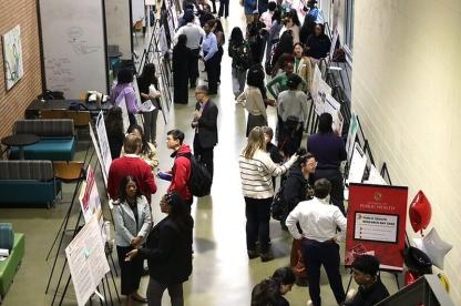 Attendees discuss research posters during Public Health Research Day in the SPH concourse.
