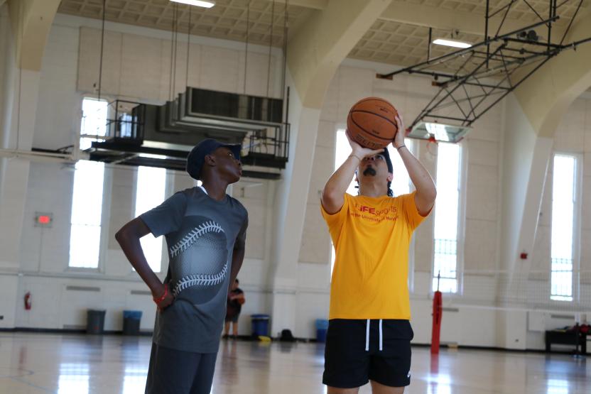 Counselor coaching kid in basketball