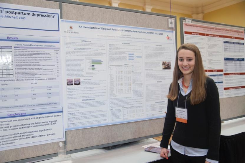 Female student posing in front of her poster presentation