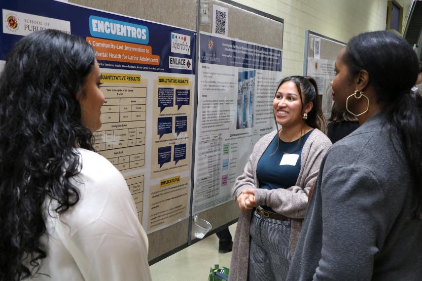 female student explaining her poster presentation to two others