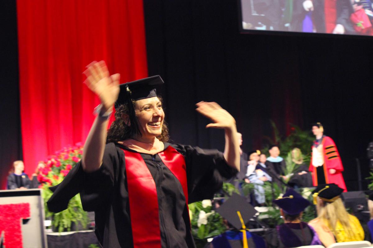 Happy student wearing a cap and gown at a commencement ceremony 