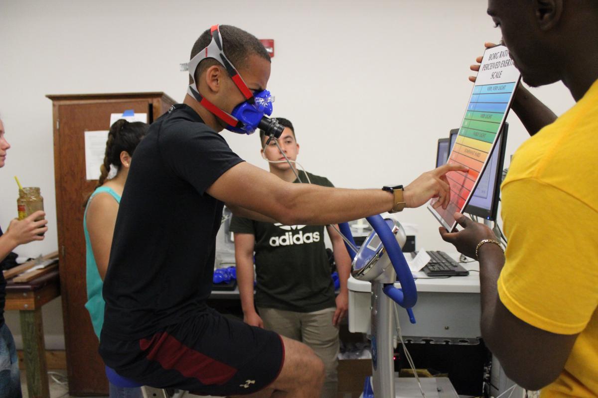 student on bike pointing to perceived exertion scale