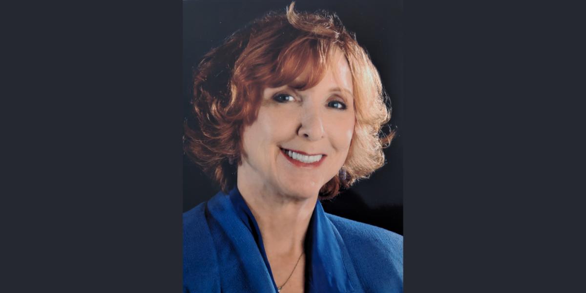 White woman professor smiles at camera
