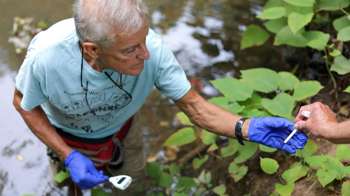 Gabe Horchler handing a pH test to another hand on the Anacostia's Quincy Run