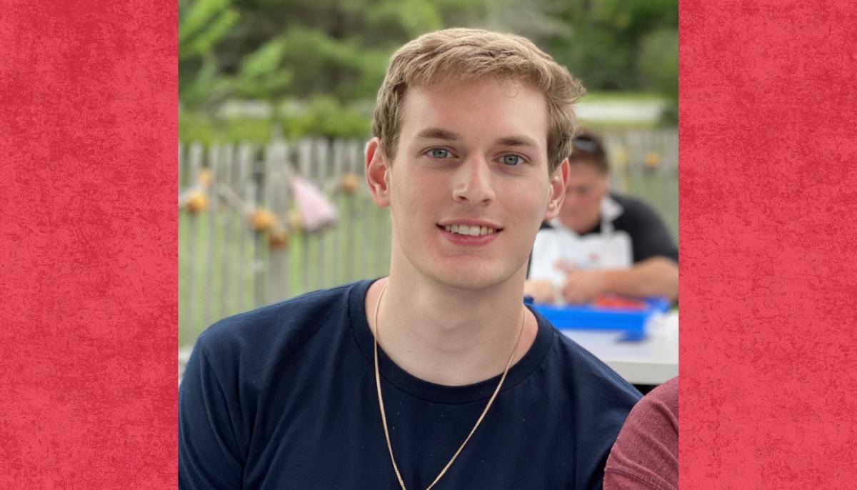 white male student wearing dark t-shirt smiles to camera