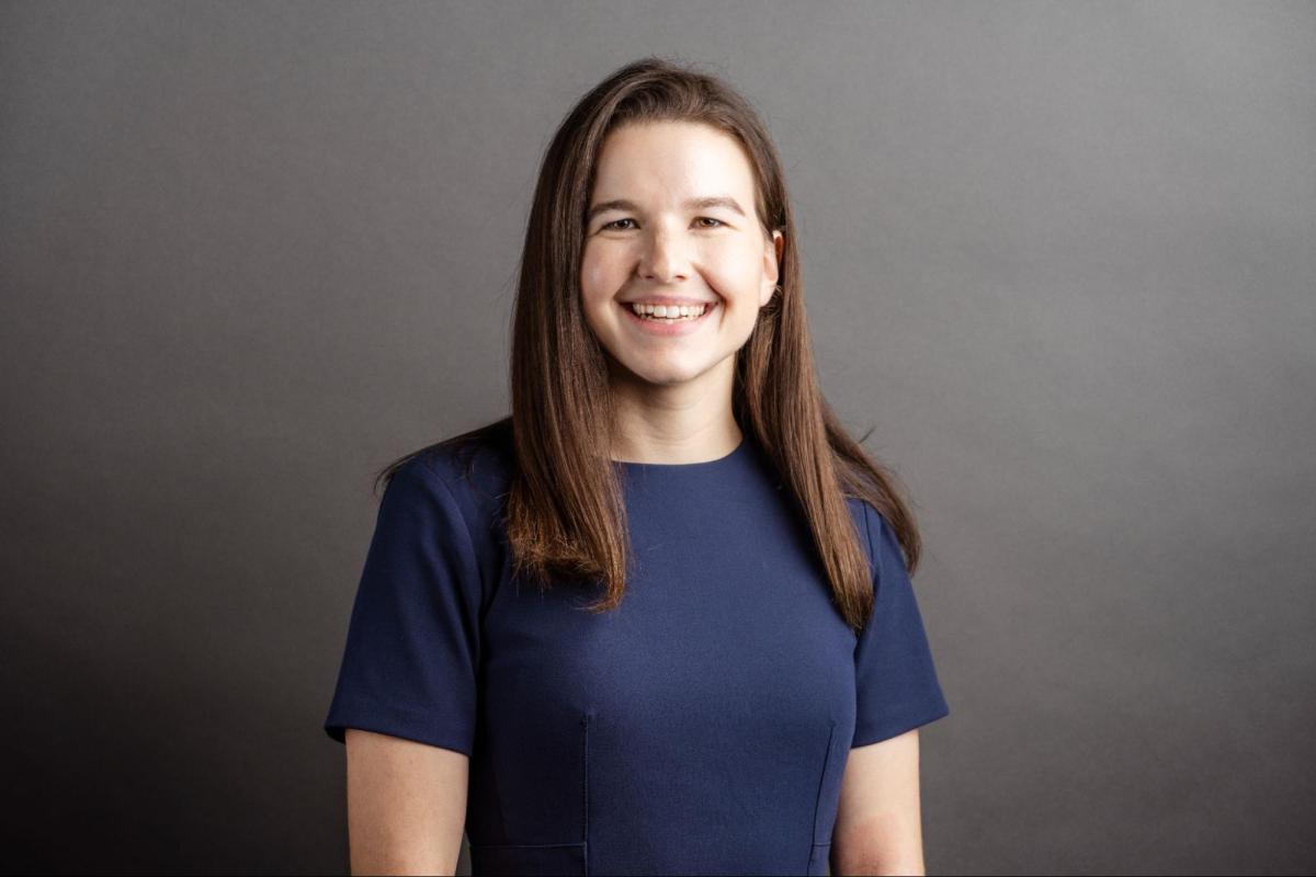 white woman in navy top with brown hair smiles at the camera