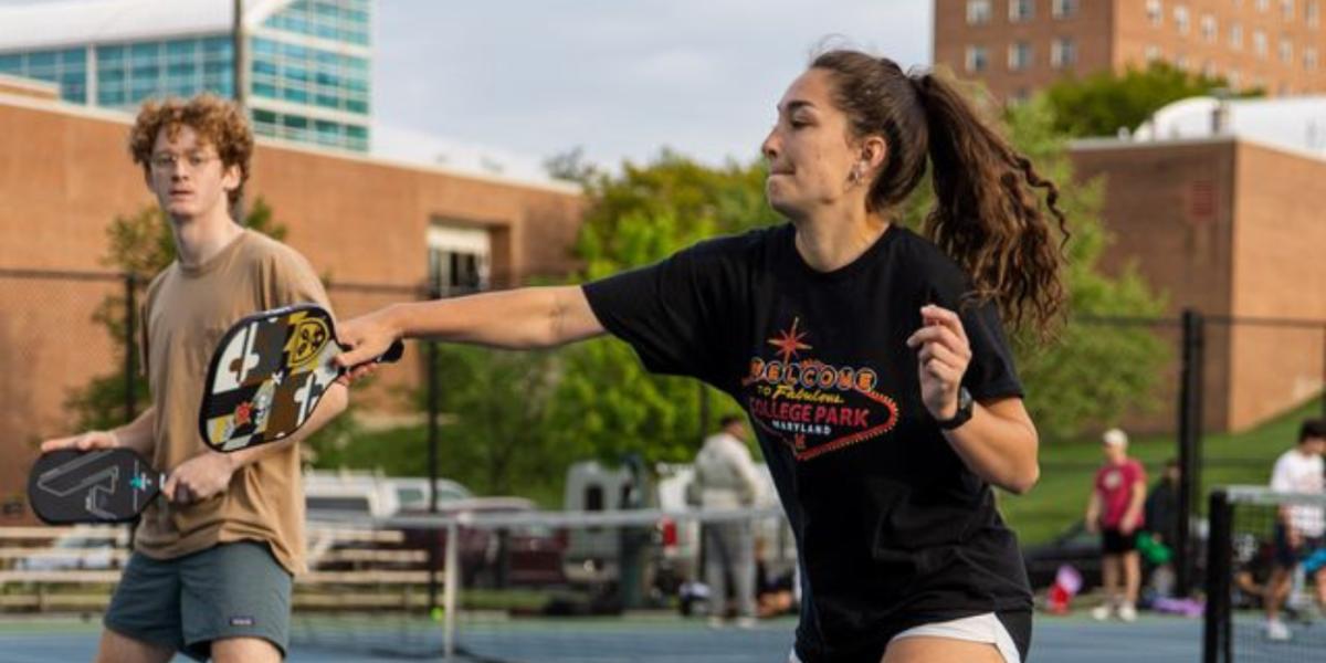 female student hits pickleball with paddle