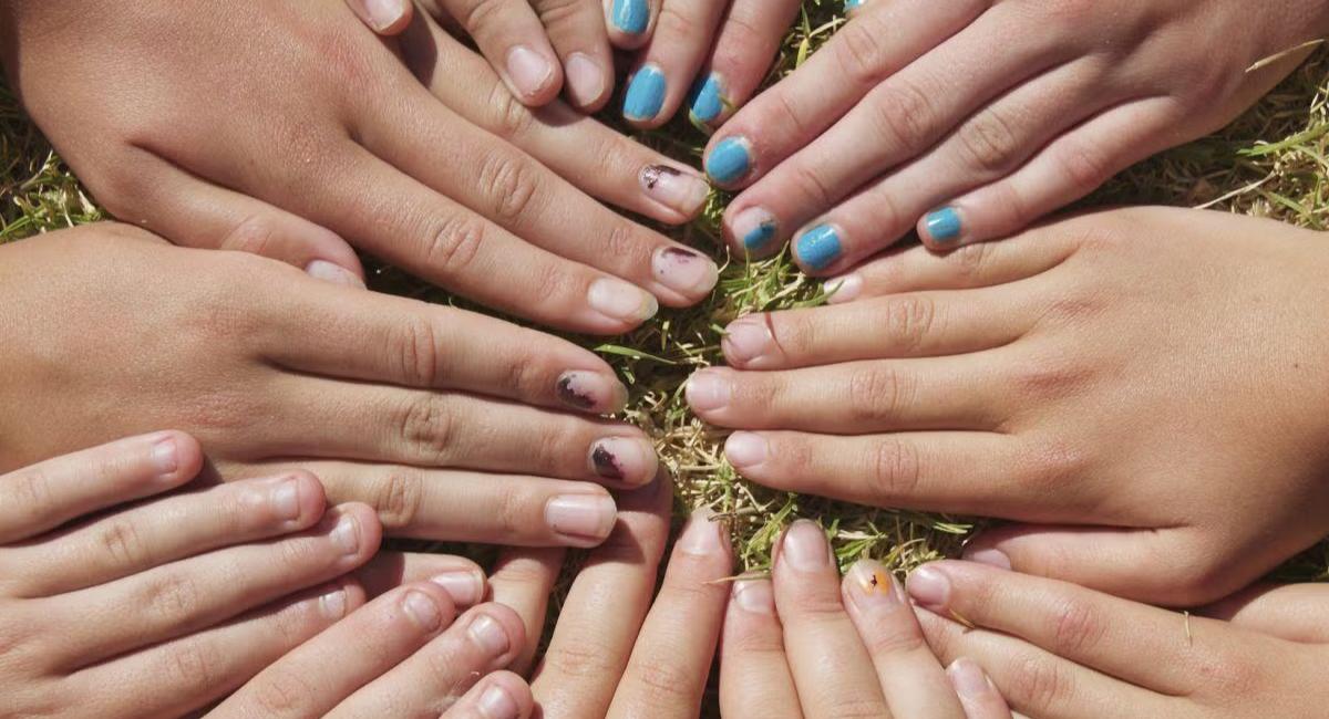 A group of diverse hands arranged in a circle on grass, symbolizing unity, collaboration, and community.