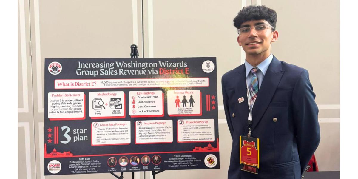 Student in jacket and tie stands with hands behind his back next to a scientific poster showing his research results