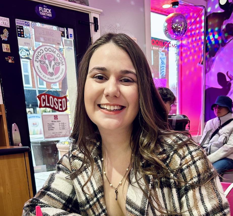 Woman with brown hair wearing a plaid top smiling at camera.